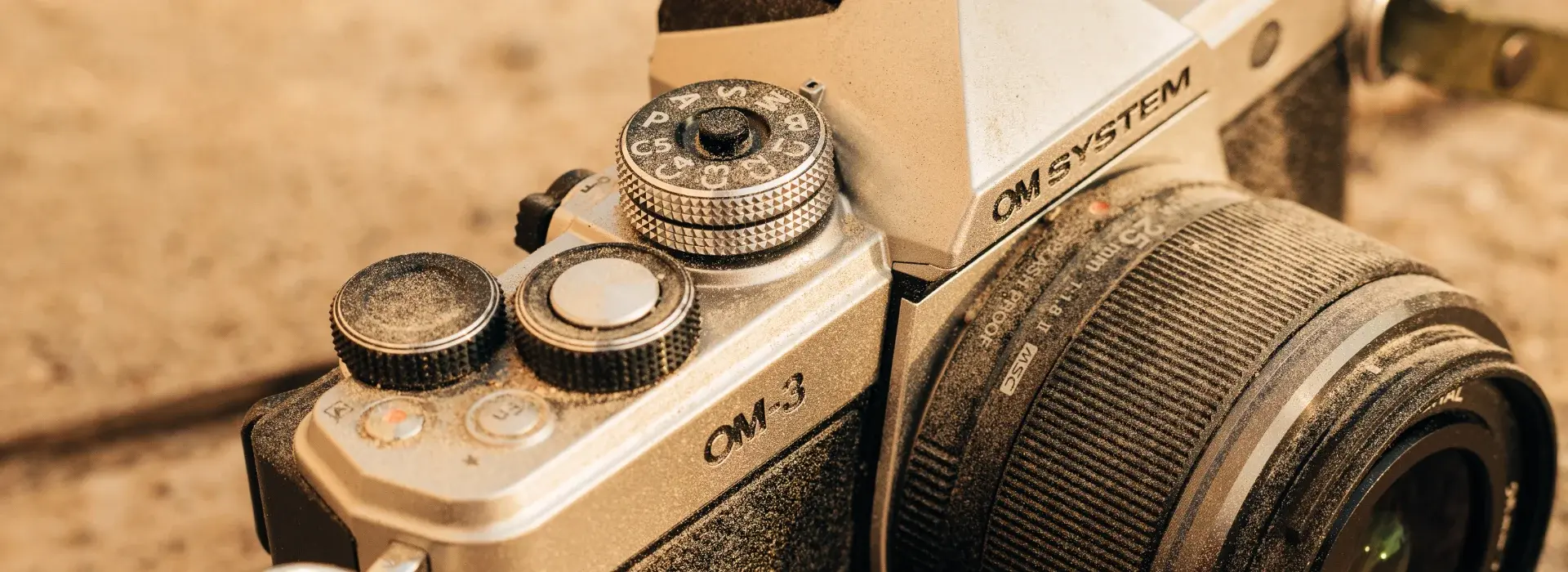 Close up shot of the OM SYSTEM OM-3 with dirt all over it.