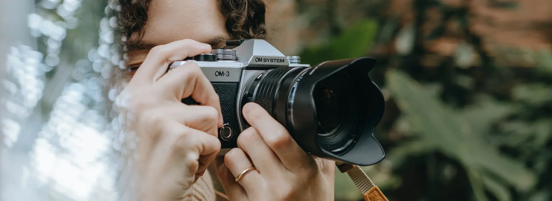 OM SYSTEM OM-3 camera in a girls hand taking a photo.