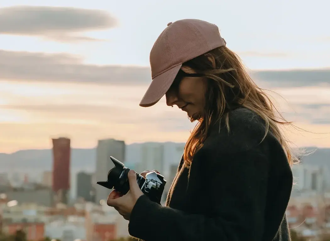 Girl looking down at her OM SYSTEM OM-3 dials to setup the next shot.