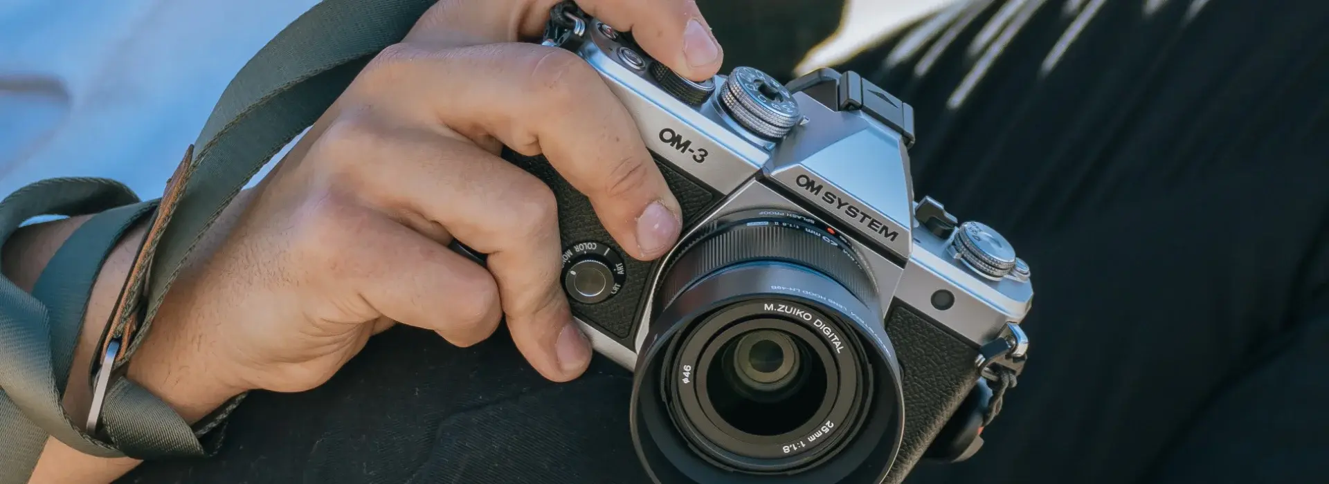 OM SYSTEM OM-3 camera in hand ready to take a photo.